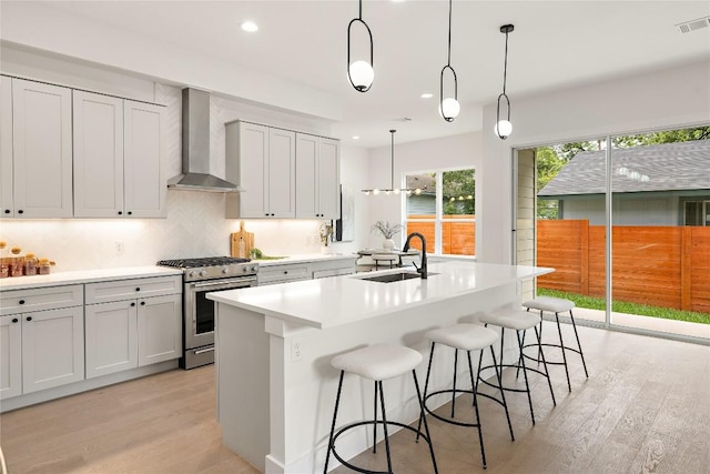 1702 Pennsylvania Ave, Austin, TX 78702 - kitchen featuring stainless steel gas range oven, wall chimney exhaust hood, a sink, light wood finished floors, and recessed lighting