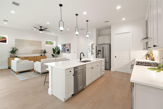 1702 Pennsylvania Ave, Austin, TX 78702 - kitchen featuring stainless steel appliances, light wood-type flooring, a sink, open floor plan, and light countertops