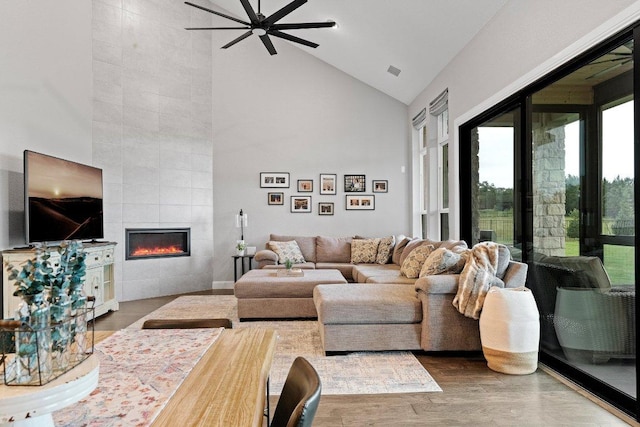 209 Northcrest Dr, Liberty Hill, TX 78642 - living room with high vaulted ceiling, ceiling fan, a tiled fireplace, and wood finished floors