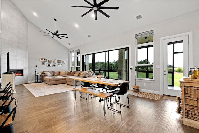209 Northcrest Dr, Liberty Hill, TX 78642 - dining room with a ceiling fan, high vaulted ceiling, wood finished floors, baseboards, and a tiled fireplace