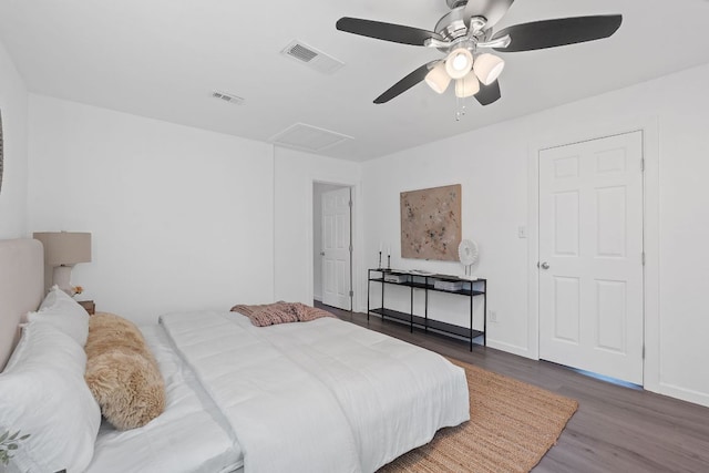 bedroom with wood finished floors, ceiling fan, baseboards, and attic access