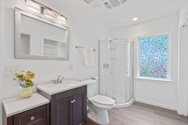 bathroom featuring wood finished floors, vanity, a stall shower, toilet, and baseboards