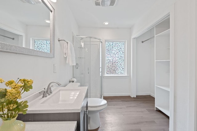 full bathroom featuring healthy amount of natural light, a shower stall, wood finished floors, vanity, and recessed lighting