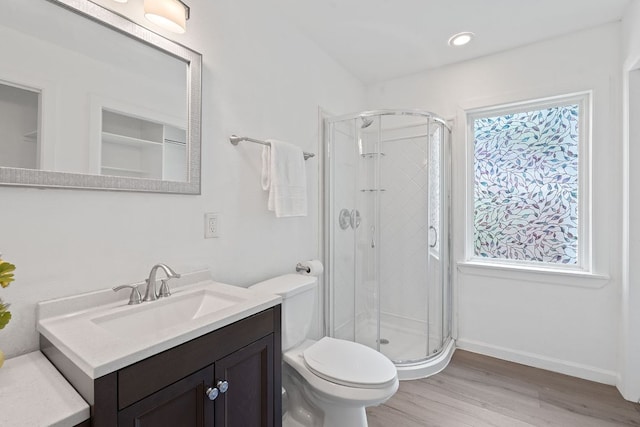 bathroom with wood finished floors, a shower stall, vanity, toilet, and recessed lighting