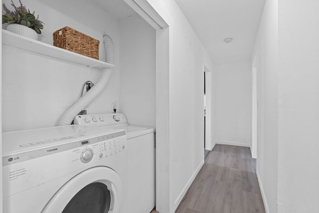 clothes washing area featuring washer and dryer, light wood-type flooring, and baseboards
