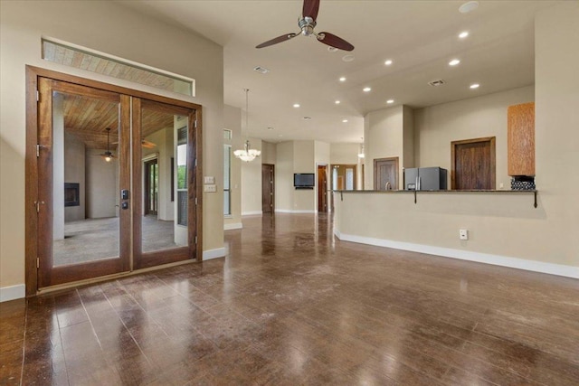 unfurnished living room featuring ceiling fan, recessed lighting, wood finished floors, baseboards, and a chandelier