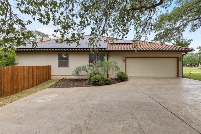 view of front facade with concrete driveway, stucco siding, a garage, roof mounted solar panels, and fence