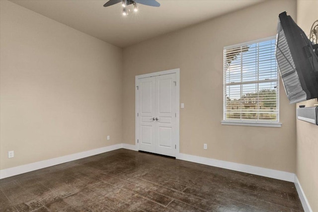 unfurnished room with ceiling fan and baseboards