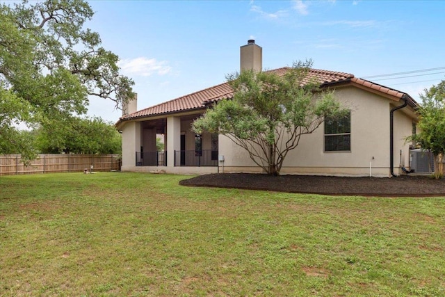 rear view of house featuring a chimney, a tiled roof, cooling unit, and stucco siding