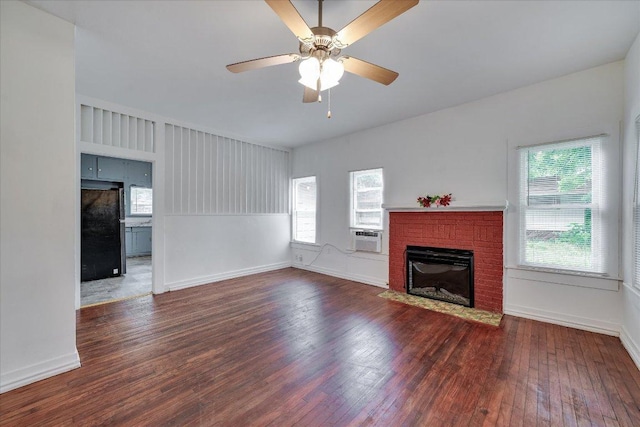 513 San Marcos Hwy, Luling, TX 78648 - unfurnished living room featuring hardwood / wood-style floors, ceiling fan, plenty of natural light, and a brick fireplace