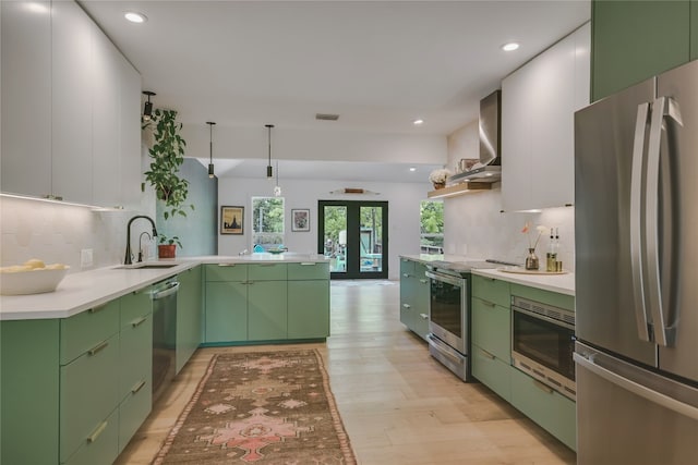 6802 Rio Bravo Ln, Austin, TX 78737 - kitchen featuring appliances with stainless steel finishes, green cabinets, a peninsula, light wood-style flooring, and backsplash