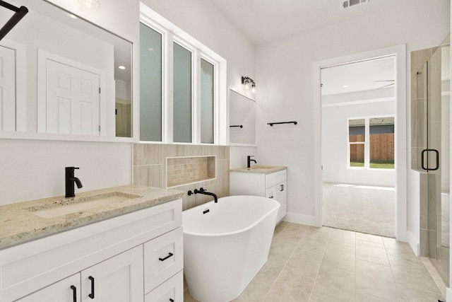 20405 Sunset Strip St, Lago Vista, TX 78645 - bathroom featuring two vanities, a shower stall, a freestanding tub, and tile patterned floors