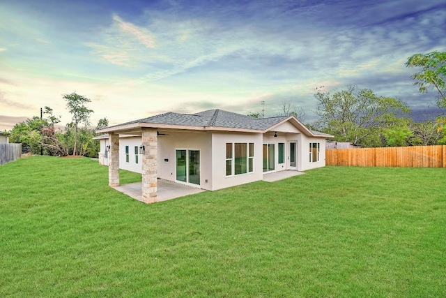 20405 Sunset Strip St, Lago Vista, TX 78645 - back of property at dusk featuring a patio area, stucco siding, roof with shingles, and stone siding