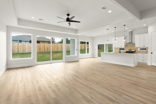 20405 Sunset Strip St, Lago Vista, TX 78645 - unfurnished living room featuring ceiling fan, a tray ceiling, light wood-style flooring, and recessed lighting