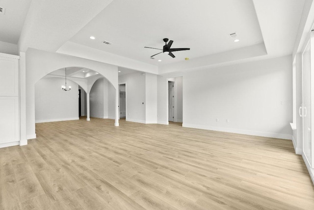 20405 Sunset Strip St, Lago Vista, TX 78645 - unfurnished living room featuring a raised ceiling, arched walkways, ceiling fan, recessed lighting, and light wood finished floors