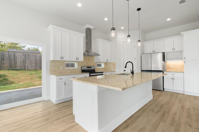 20405 Sunset Strip St, Lago Vista, TX 78645 - kitchen featuring appliances with stainless steel finishes, wall chimney range hood, recessed lighting, white cabinetry, and a kitchen island with sink