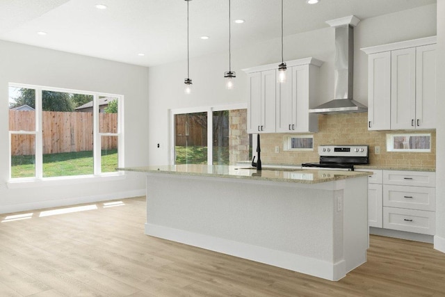 20405 Sunset Strip St, Lago Vista, TX 78645 - kitchen featuring wall chimney exhaust hood, range with electric stovetop, tasteful backsplash, light wood-type flooring, and white cabinetry