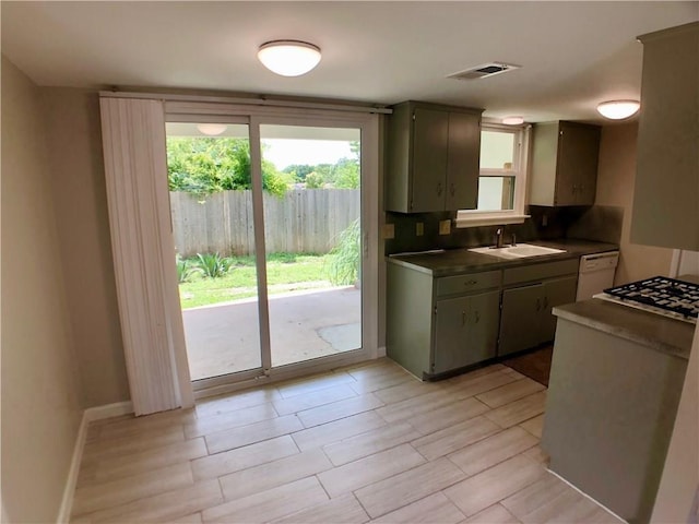 8502 Woodstone Dr, Austin, TX 78757 - kitchen featuring a sink, dark countertops, dishwasher, stainless steel gas cooktop, and baseboards