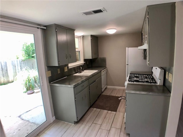 8502 Woodstone Dr, Austin, TX 78757 - kitchen with white appliances, a sink, gray cabinets, under cabinet range hood, and light wood-type flooring