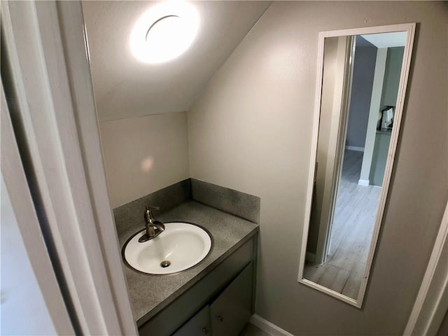 8502 Woodstone Dr, Austin, TX 78757 - bathroom with vanity, wood finished floors, baseboards, and vaulted ceiling