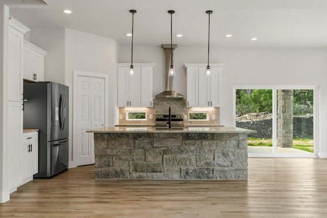 8800 Bar K Ranch Rd, Lago Vista, TX 78645 - kitchen with appliances with stainless steel finishes, wall chimney exhaust hood, light wood-type flooring, white cabinets, and tasteful backsplash