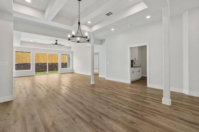 8800 Bar K Ranch Rd, Lago Vista, TX 78645 - unfurnished living room featuring a chandelier, ceiling fan, recessed lighting, wood finished floors, and a raised ceiling
