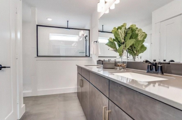 full bathroom with double vanity, a shower, and baseboards