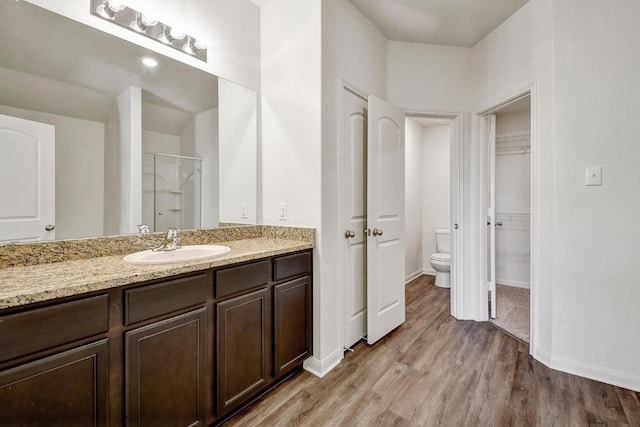 1174 Amy Dr, Kyle, TX 78640 - bathroom with toilet, wood finished floors, a shower stall, baseboards, and vanity