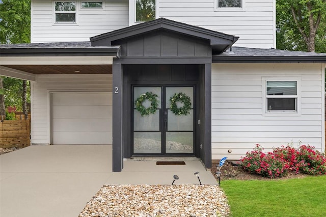 4423 Jinx Ave Unit 2, Austin, TX 78745 - doorway to property with a garage, concrete driveway, a shingled roof, a lawn, and board and batten siding