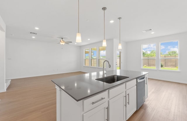 kitchen featuring a sink, stainless steel dishwasher, light wood-style floors, recessed lighting, and an island with sink