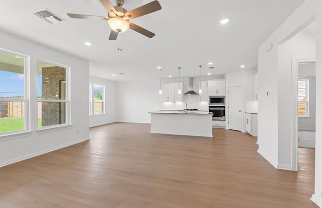 unfurnished living room with light wood-style flooring, a sink, a ceiling fan, recessed lighting, and baseboards
