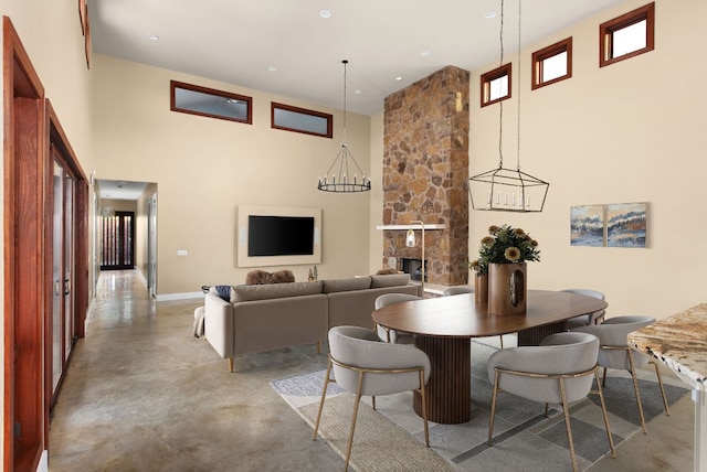 9208 Madrone Ranch Trl, Austin, TX 78738 - dining area featuring a towering ceiling, concrete floors, baseboards, and a stone fireplace