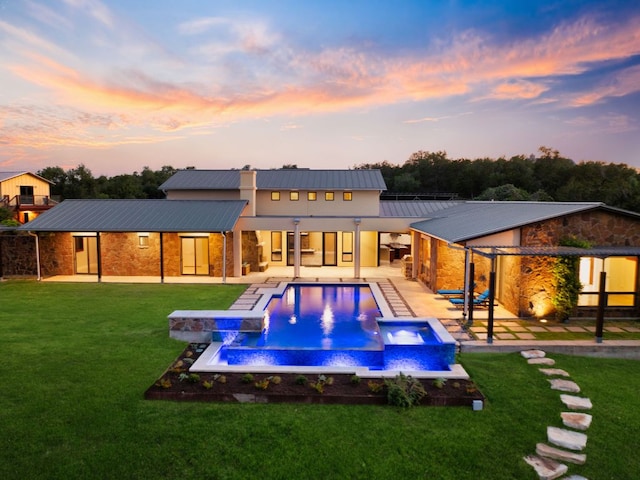 9208 Madrone Ranch Trl, Austin, TX 78738 - back of property at dusk with stone siding, metal roof, a pool with connected hot tub, and a patio area