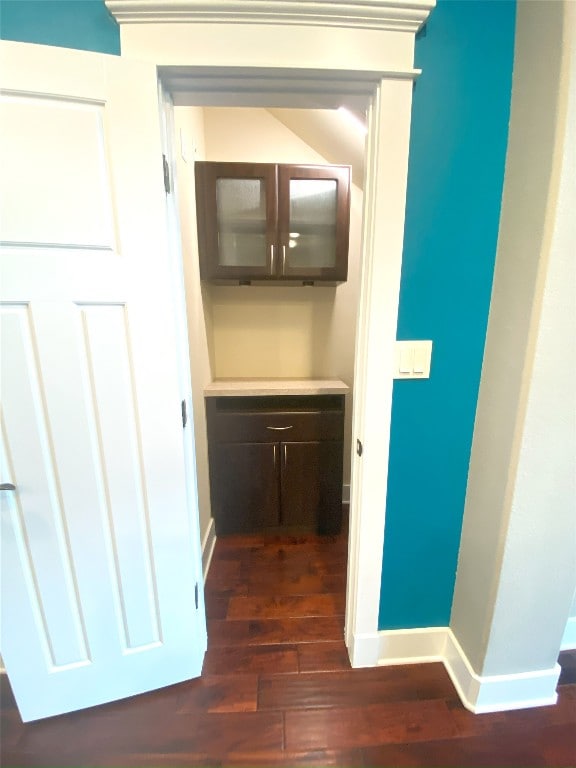 hallway featuring dark wood-type flooring and baseboards