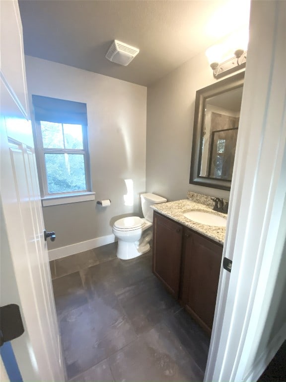 bathroom with toilet, vanity, and baseboards