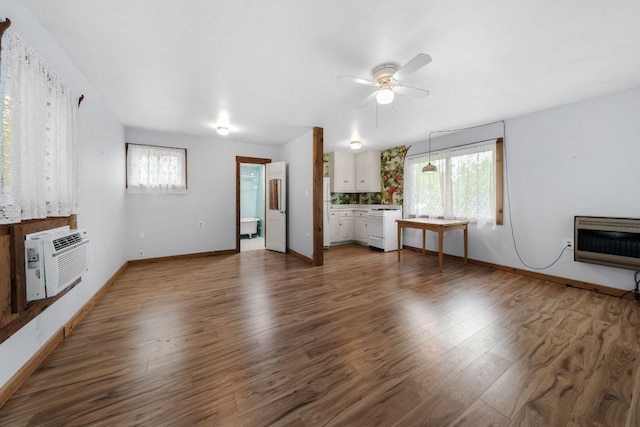 512 E 49th St, Austin, TX 78751 - unfurnished living room featuring heating unit, ceiling fan, wood finished floors, and a wall mounted air conditioner
