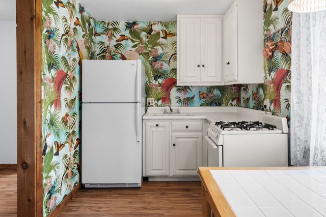 512 E 49th St, Austin, TX 78751 - kitchen featuring white appliances, wallpapered walls, light countertops, white cabinetry, and wood finished floors