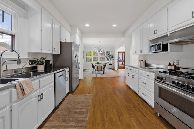 512 E 49th St, Austin, TX 78751 - kitchen with appliances with stainless steel finishes, white cabinets, a chandelier, wood finished floors, and recessed lighting