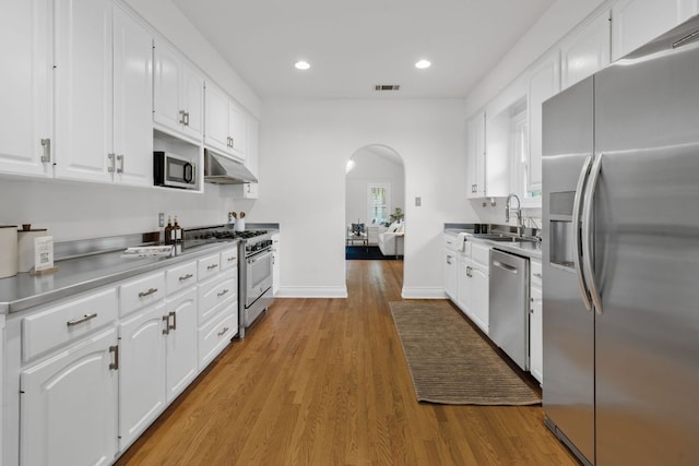 512 E 49th St, Austin, TX 78751 - kitchen featuring appliances with stainless steel finishes, under cabinet range hood, arched walkways, white cabinetry, and recessed lighting