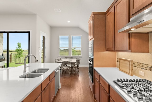 kitchen featuring a sink, under cabinet range hood, appliances with stainless steel finishes, brown cabinets, and light countertops