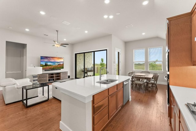 kitchen featuring stainless steel appliances, a sink, recessed lighting, brown cabinets, and wood finished floors