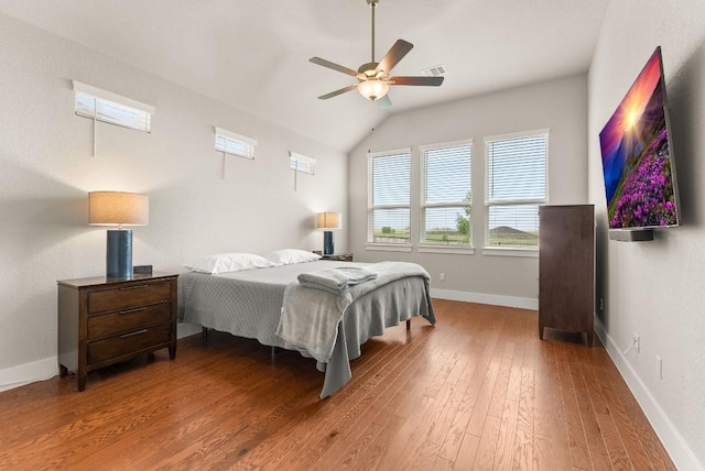 bedroom with wood finished floors, lofted ceiling, baseboards, and a ceiling fan