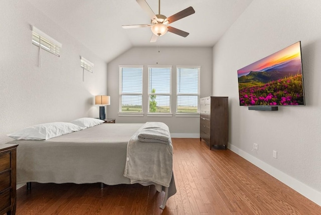 bedroom with wood-type flooring, vaulted ceiling, baseboards, and ceiling fan