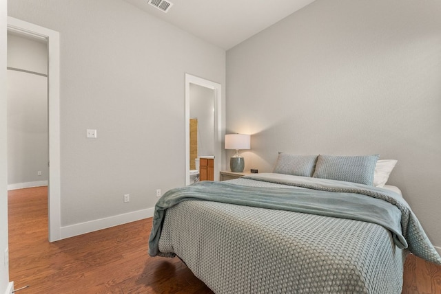 bedroom with wood finished floors, baseboards, and ensuite bath