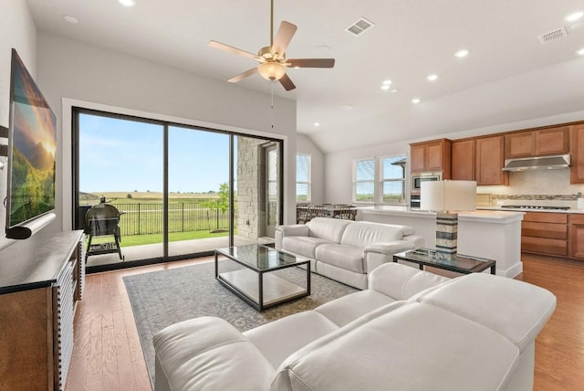 living area featuring light wood finished floors, a ceiling fan, recessed lighting, and vaulted ceiling
