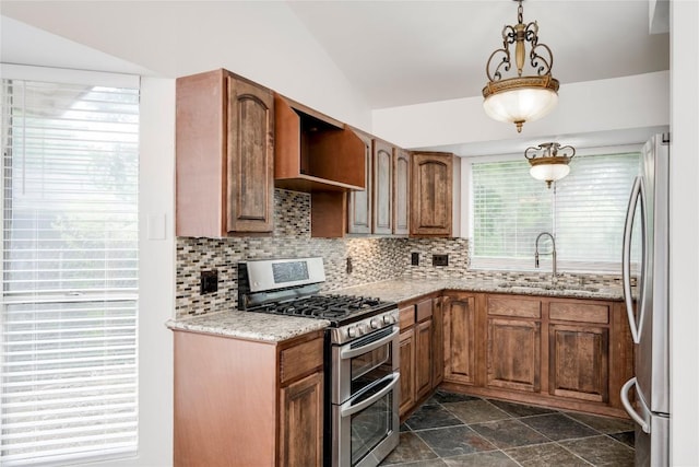 4703 Quicksilver Blvd, Austin, TX 78744 - kitchen featuring appliances with stainless steel finishes, tasteful backsplash, lofted ceiling, brown cabinetry, and dark stone finish floors