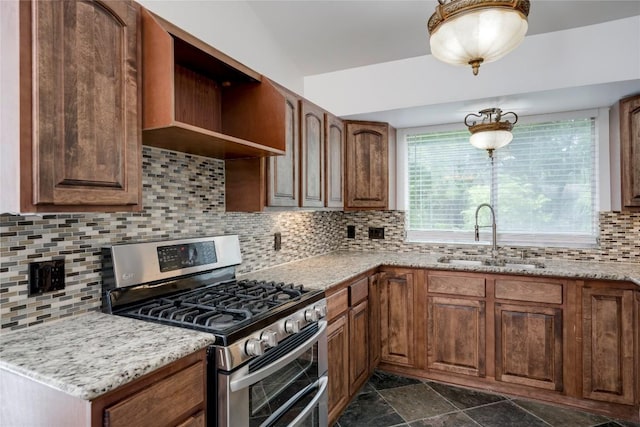 4703 Quicksilver Blvd, Austin, TX 78744 - kitchen featuring gas stove, backsplash, dark stone finish flooring, brown cabinetry, and light stone counters