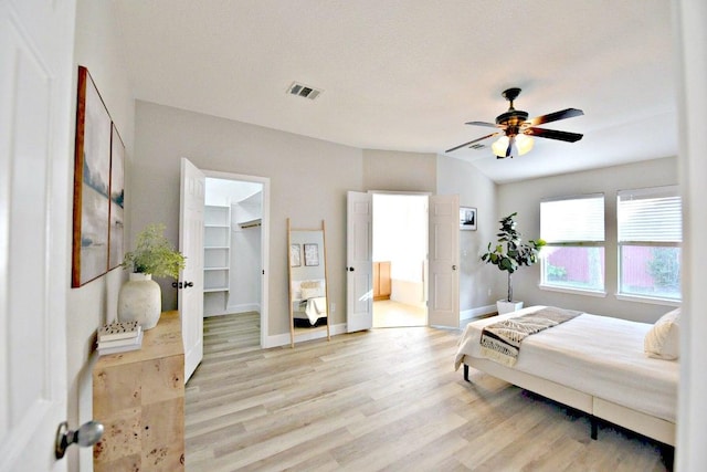 11120 Old Quarry Rd, Austin, TX 78717 - bedroom featuring light wood finished floors, a spacious closet, baseboards, ensuite bathroom, and a ceiling fan