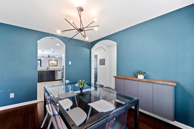 dining area with arched walkways, a chandelier, wood finished floors, baseboards, and recessed lighting