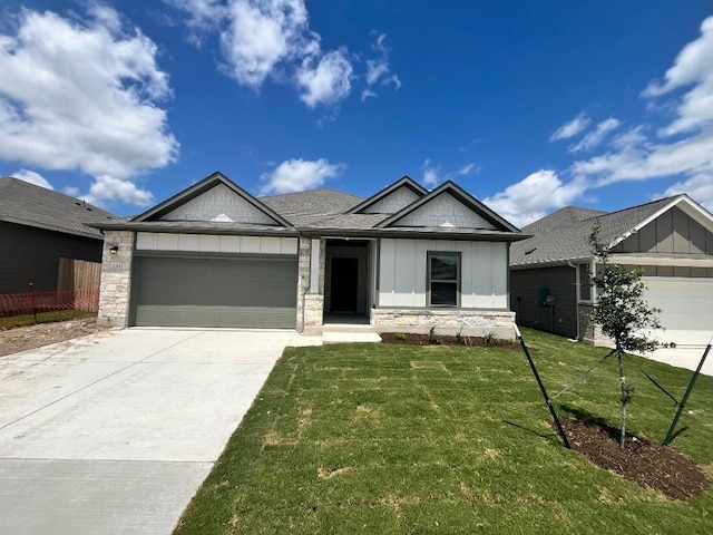 264 Little Green Trl, Jarrell, TX 76537 - view of front facade with a garage, board and batten siding, a front lawn, concrete driveway, and stone siding